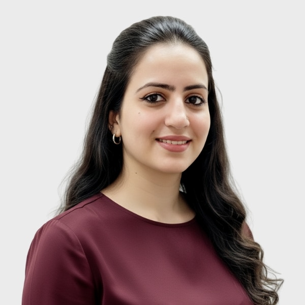 A woman with long dark hair, wearing hoop earrings and a maroon top, smiles slightly while facing the camera against a plain light background, reflecting the professional style of an IT staffing agency in Toronto.