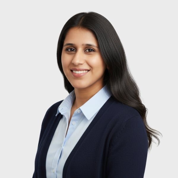 A woman with long, dark hair smiles at the camera. She wears a light blue collared shirt and a dark blue sweater, posing confidently against a plain background—reflecting the professional spirit of an IT staffing agency in Toronto.