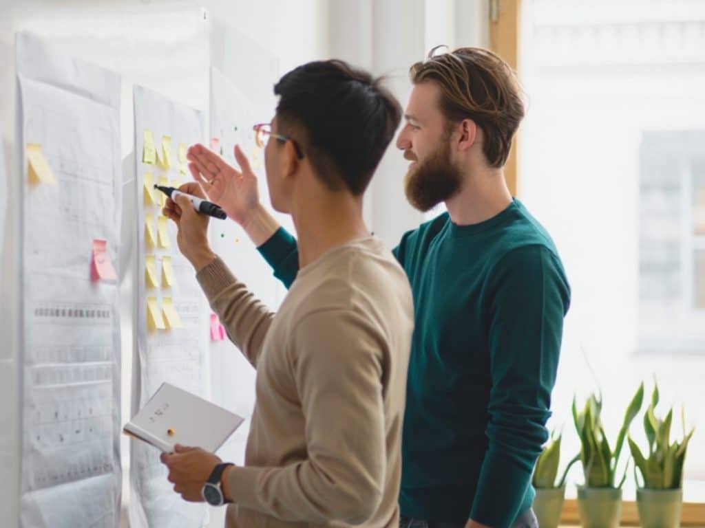 Two men collaborating on a marker board
